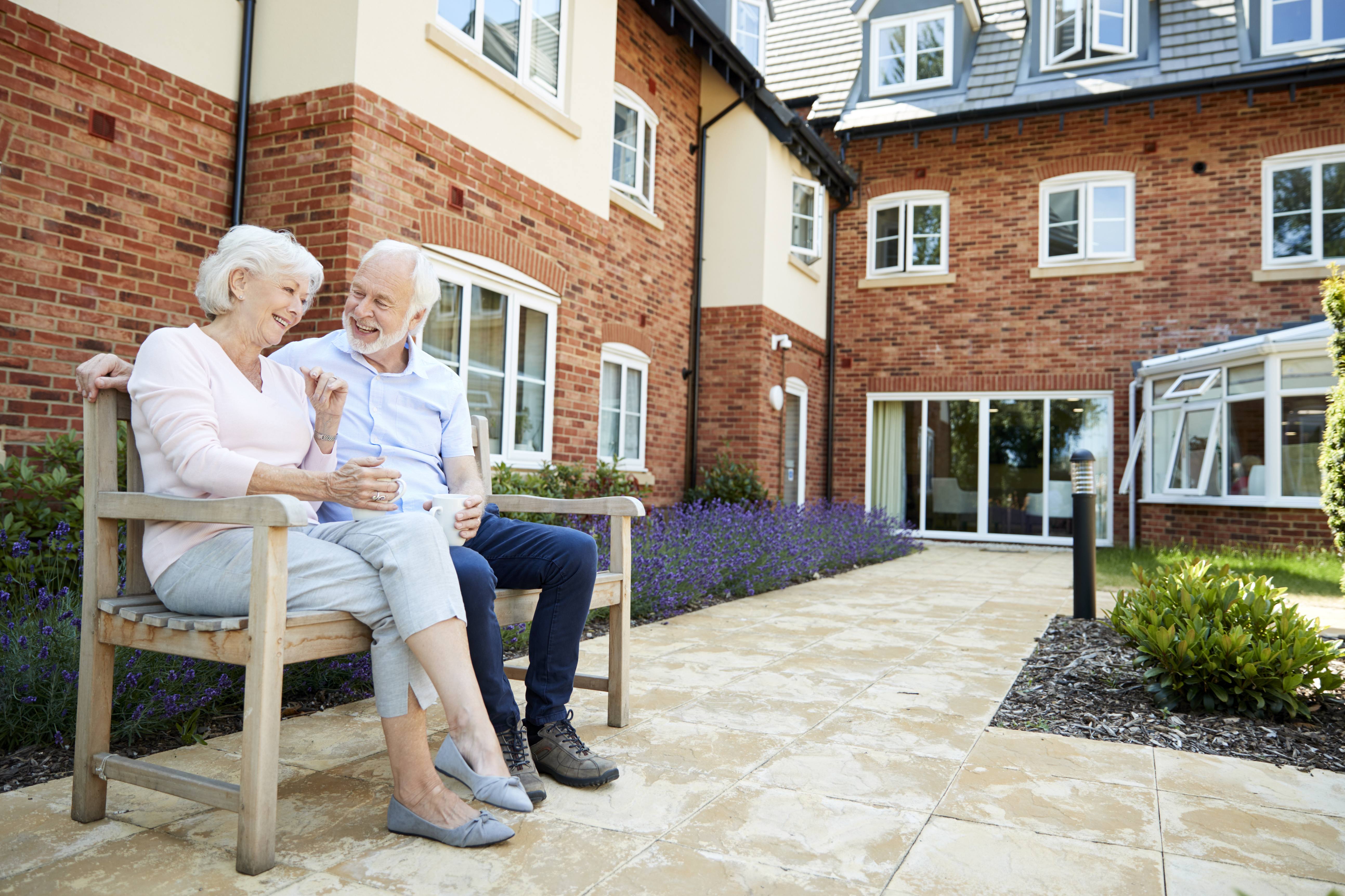 retired-couple-sitting-on-bench-with-hot-drink-in--EMF8DNP-1